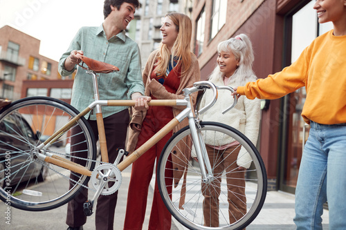 Group Of Multi-Cultural Friends On City Street Lifting Sustainable Bamboo Bicycle 