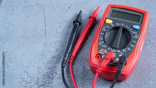 Red multimeter or a multitester, also known as a VOM on gray table. Electronic measuring instrument. Red and black wires