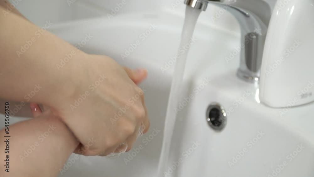 Close up of female and childrens washing hands with antibacterial soap with foam under tap in white sink. Care and hygiene concept. Concept of disinfection against Coronovirus Close up of female and childrens washing hands with antibacterial soap with foam under tap in white sink. Care and hygiene concept. Concept of disinfection against Coronovirus