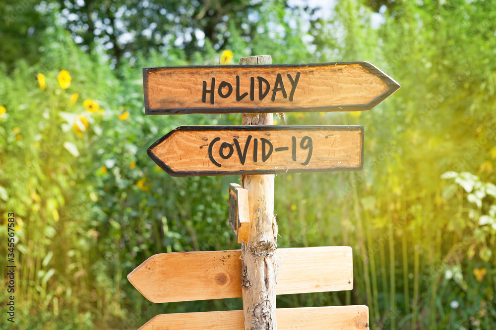 Wooden direction sign with  words Holiday and Covid-19