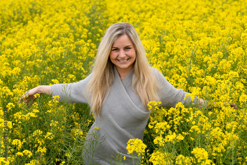 Fototapeta premium Young woman suffers from allergy in a rape field and has to sneeze