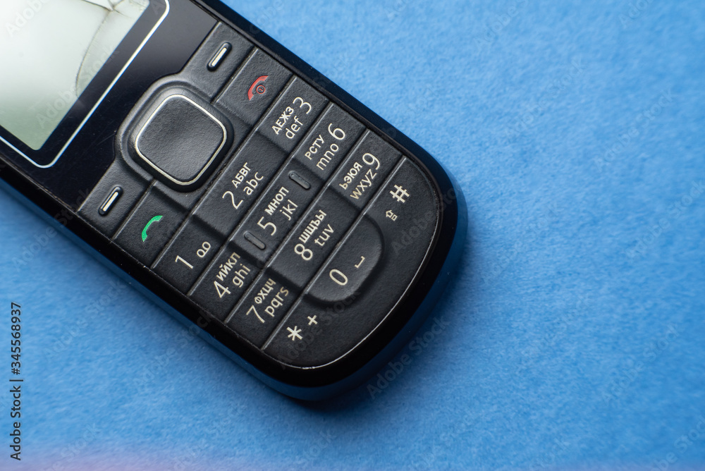 old push-button cell phone on blue background old push-button cell phone on blue background
