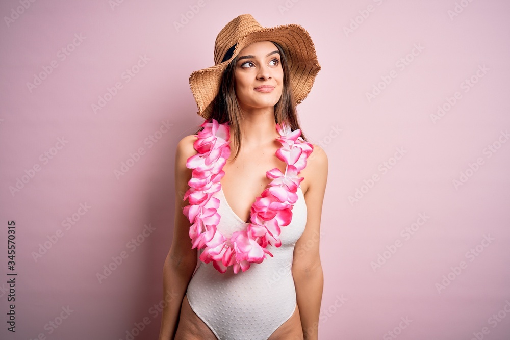 Young beautiful brunette woman on vacation wearing swimsuit and Hawaiian flowers lei smiling looking to the side and staring away thinking. Young beautiful brunette woman on vacation wearing swimsuit and Hawaiian flowers lei smiling looking to the side and staring away thinking.