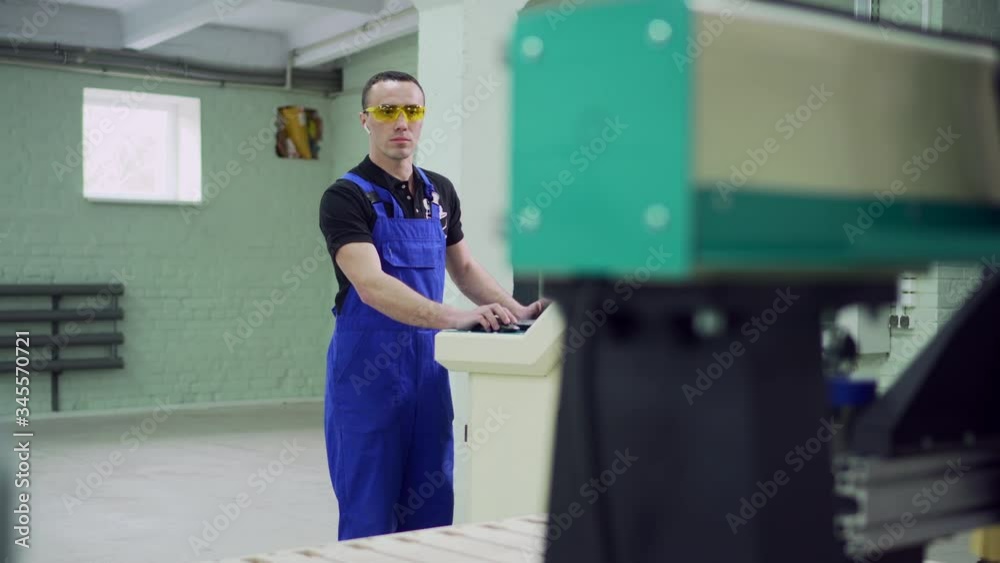 A male operator controls the CNC machine while standing at the control panel. A male operator controls the CNC machine while standing at the control panel.