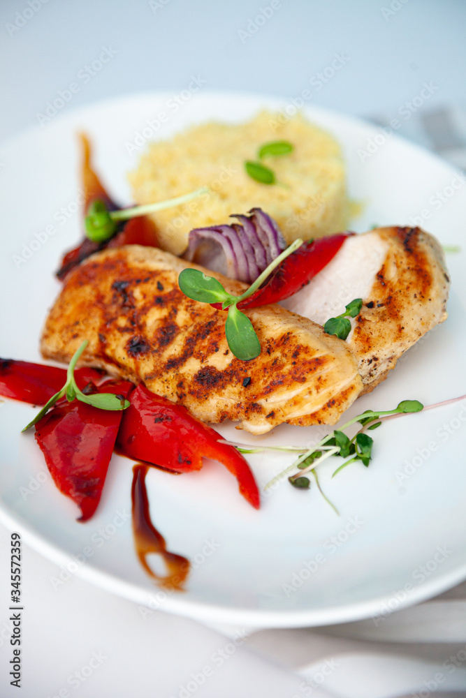 Grilled chicken fillet and pepper. Meat and porridge in a plate with microgreen. White plate with home food close-up. Cutlet and vegetables. Mashed potatoes and a piece of meat.