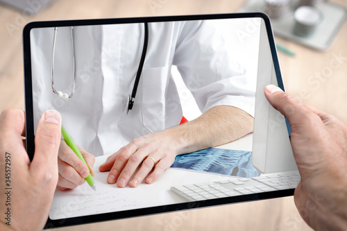 Docteur médecin en téléconsultation avec tablette et main du patient à domicile photo
