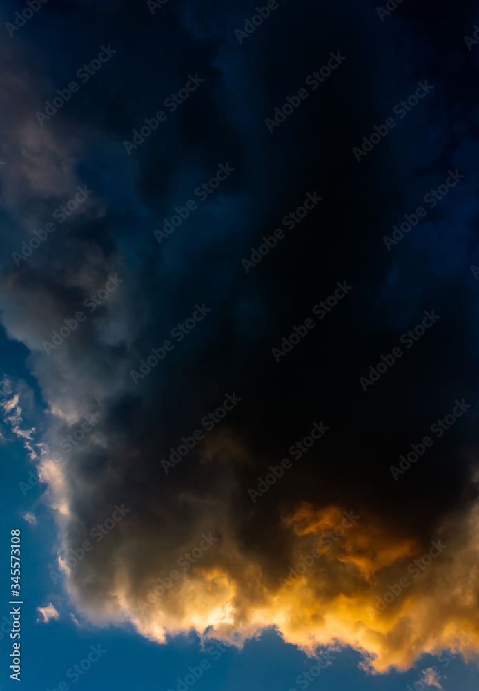 Dark clouds drenched in sunset hues against a blue sky