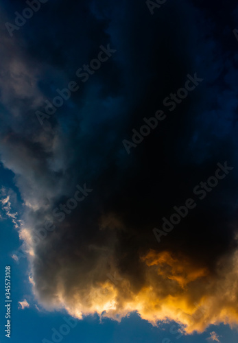 Dark clouds drenched in sunset hues against a blue sky