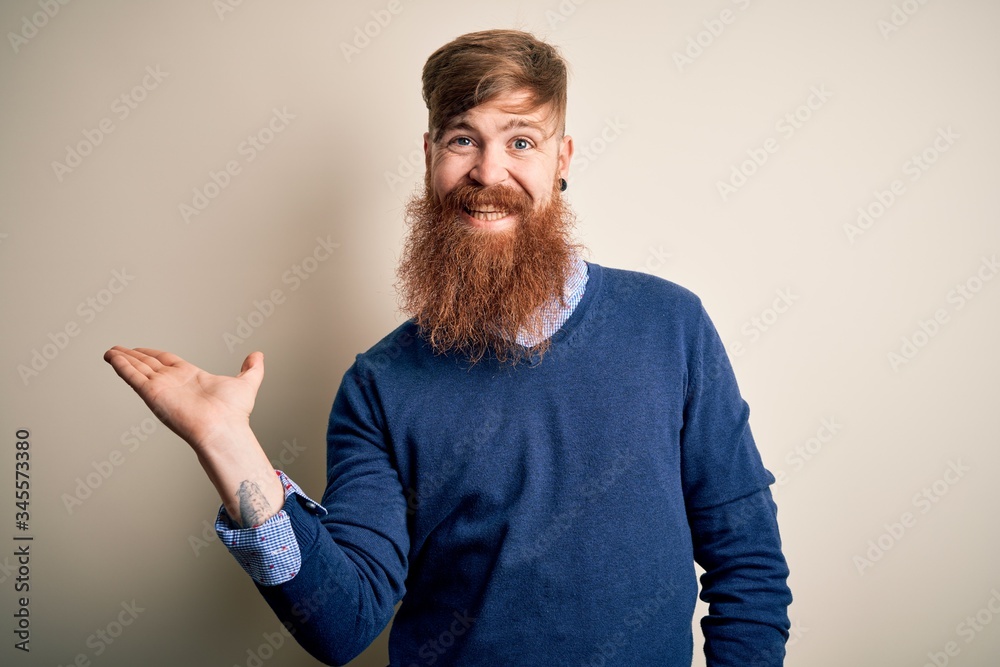 Handsome Irish redhead business man with beard standing over isolated background smiling cheerful presenting and pointing with palm of hand looking at the camera. Handsome Irish redhead business man with beard standing over isolated background smiling cheerful presenting and pointing with palm of hand looking at the camera.