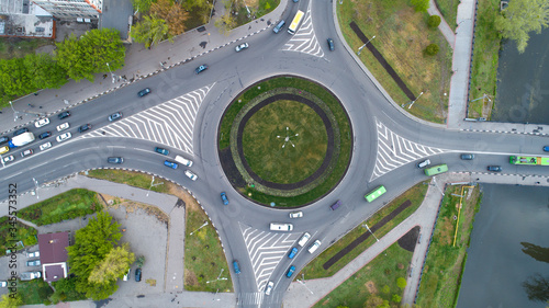 Ring road from the high with green grass circle inside and cars traffic.Aerial view of highway interchange in city,