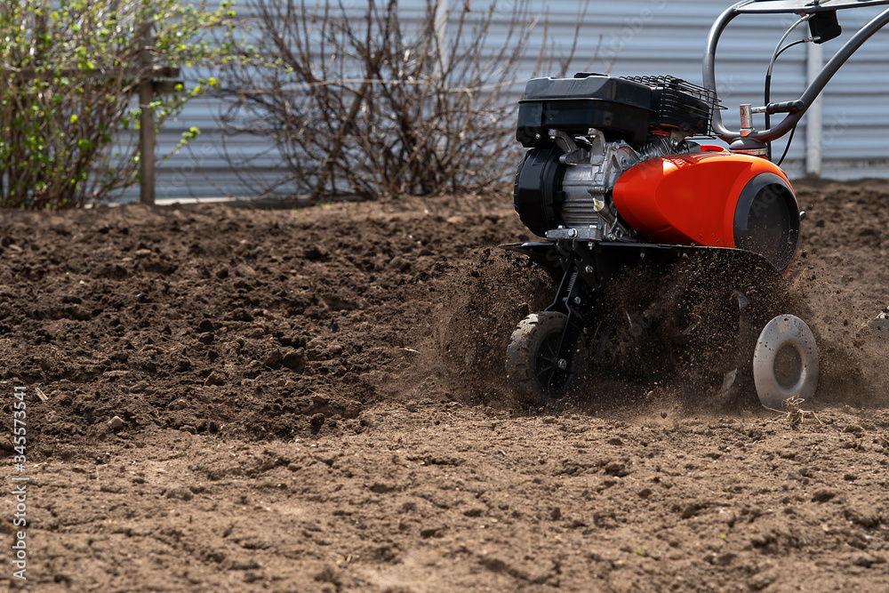 The cultivator digs the earth, clods of earth fly out from under the cultivator The cultivator digs the earth, clods of earth fly out from under the cultivator