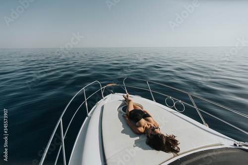 Young attractive woman relaxing on luxury yacht floating on ablue sea photo