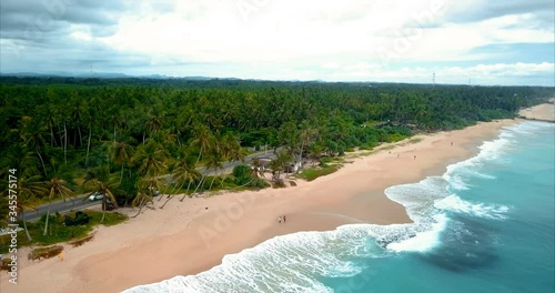 Sunny beach, golden sand and blue ocean and green palm trees, beautiful view from the drone.