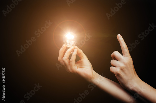 A light bulb in a woman's hand on back background