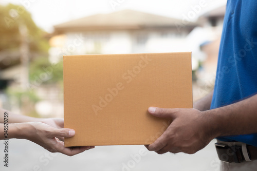 Woman hand accepting a delivery boxes of paper containers from deliveryman. © Patcharin