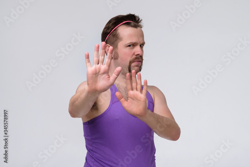 Young man with mustache coving away hands palms showing refusal and denial gesture photo