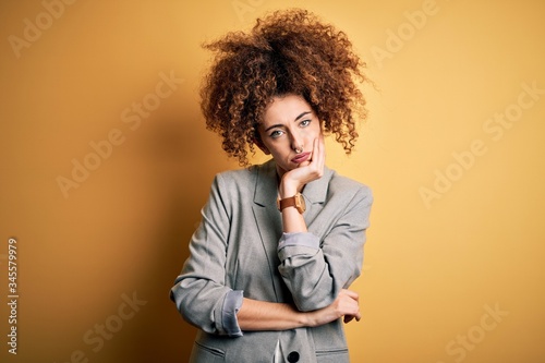 Young beautiful businesswoman with curly hair and piercing wearing elegant jacket thinking looking tired and bored with depression problems with crossed arms. © Krakenimages.com