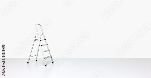 Stehleiter aus Metall vor einer weißen Wand