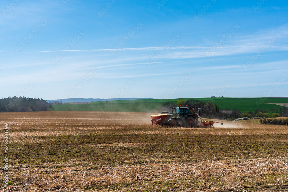 Obraz premium Farmer in tractor sowing wheat field at spring , czech jeseniky 04.16.2020