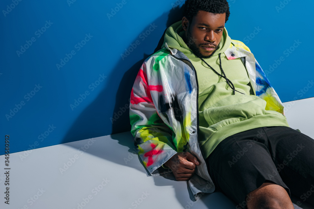 handsome african american man posing in colorful futuristic look on grey and blue handsome african american man posing in colorful futuristic look on grey and blue