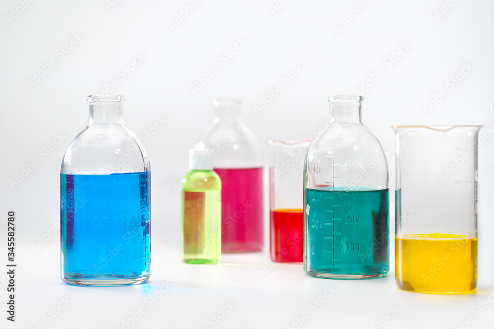 Glass bottles and flasks of different sizes with liquids of different colors on the background. Chemical lab. Glass bottles and flasks of different sizes with liquids of different colors on the background. Chemical lab.
