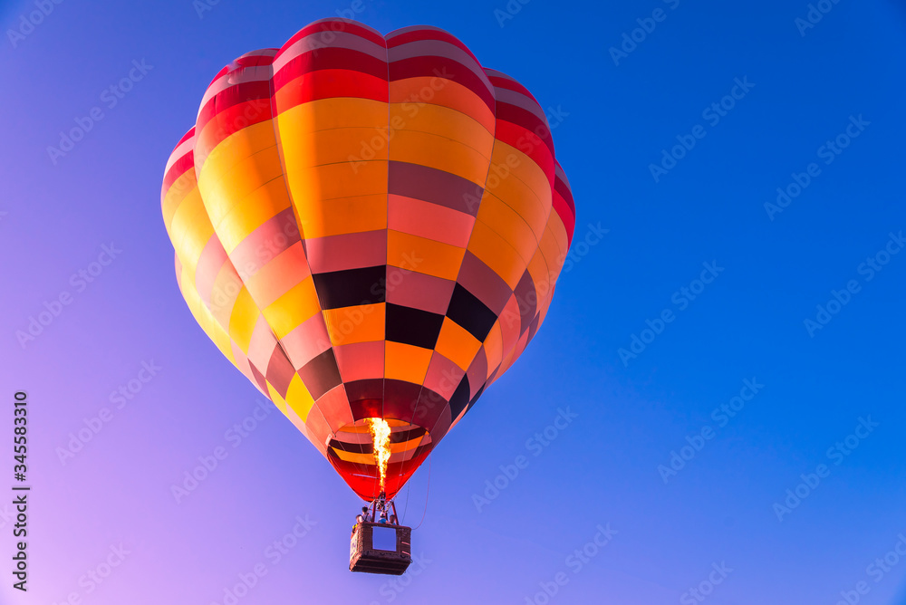 Fototapeta premium Close up hot air balloon flying up on cosmos field with blue sky background