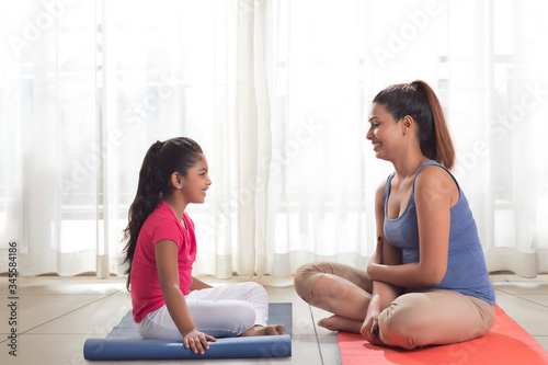 Mother and daughter sitting on exercise mat 