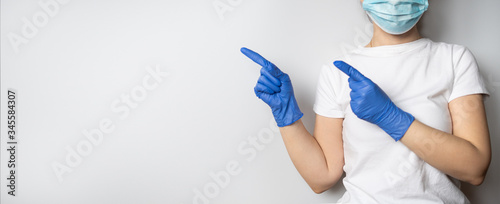 A doctor or nurse wearing protective blue medical latex gloves and a face mask on a grey or white background. Healthcare. Concept of infection control. Copy space.
