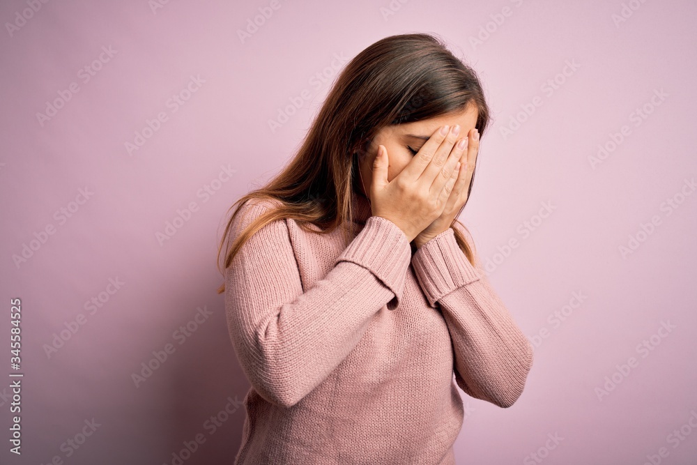 Beautiful young woman wearing turtleneck sweater over pink isolated background with sad expression covering face with hands while crying. Depression concept. Beautiful young woman wearing turtleneck sweater over pink isolated background with sad expression covering face with hands while crying. Depression concept.