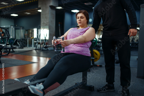 Overweight woman with trainer in sport club