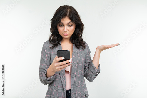 brunette girl in a gray jacket with a phone in his hands communicates on an isolated white background