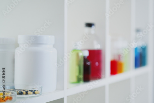 Many different bottles and test tubes with liquids of different colors stand on the shelf. Pharmacy.