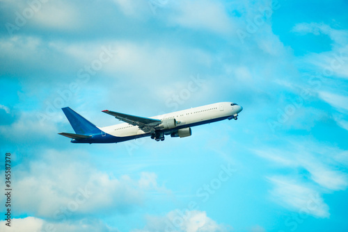 View of big white flying plane on blue sky and clouds background
