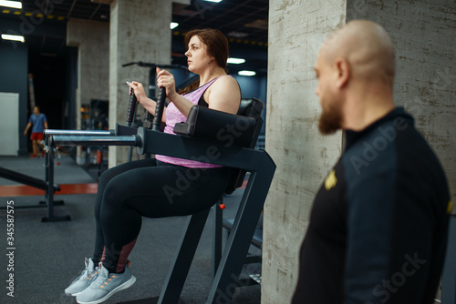 Tired overweight girl with trainer in sport club