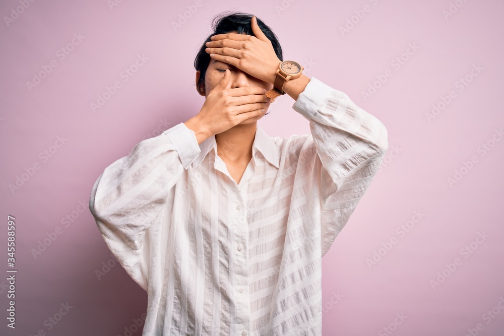 Young beautiful asian girl wearing casual shirt standing over isolated pink background Covering eyes and mouth with hands, surprised and shocked. Hiding emotion Young beautiful asian girl wearing casual shirt standing over isolated pink background Covering eyes and mouth with hands, surprised and shocked. Hiding emotion