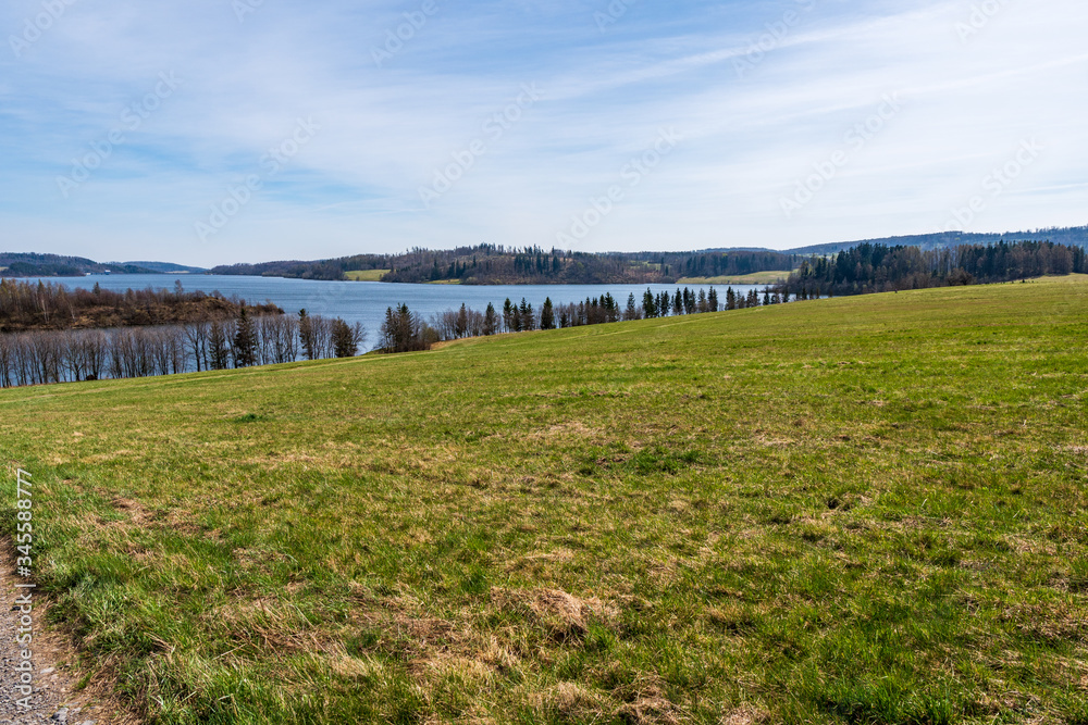 pasture with beautiful lake and blue-white sky on a sunny day