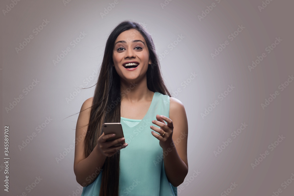Portrait of a happy teenage girl holding her mobile phone and laughing
Portrait of a happy teenage girl holding her mobile phone and laughing