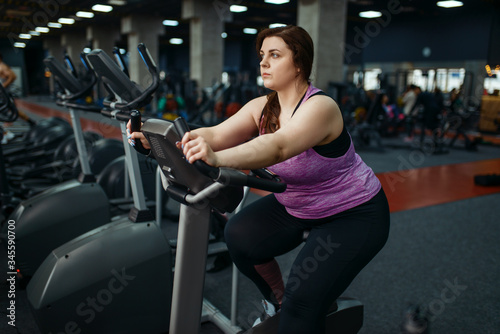 Overweight woman trains on exercise bike in gym