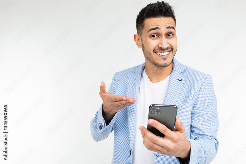 smiling stylish brunette man in a blue jacket looks at the phone on a white background smiling stylish brunette man in a blue jacket looks at the phone on a white background