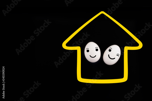 A white chicken easter egg in a medical mask in a painted house isolated on black background. Protection Concepts with Corona Virus (COVID19). Stay at home. Safety comes first during Easter 2020.