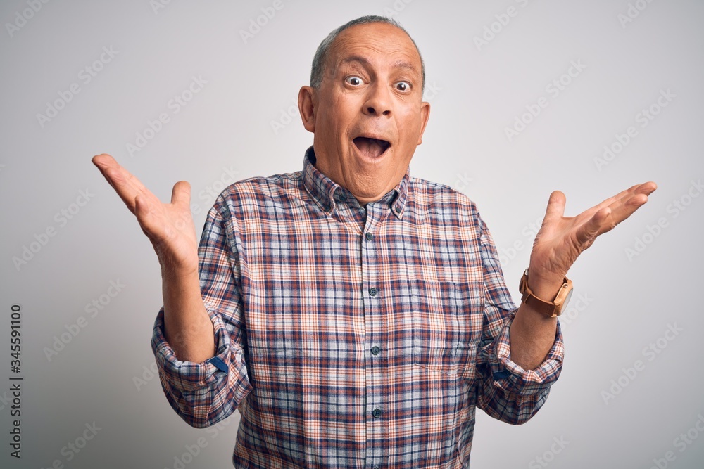 Senior handsome man wearing casual shirt standing over isolated white background celebrating crazy and amazed for success with arms raised and open eyes screaming excited. Winner concept Senior handsome man wearing casual shirt standing over isolated white background celebrating crazy and amazed for success with arms raised and open eyes screaming excited. Winner concept