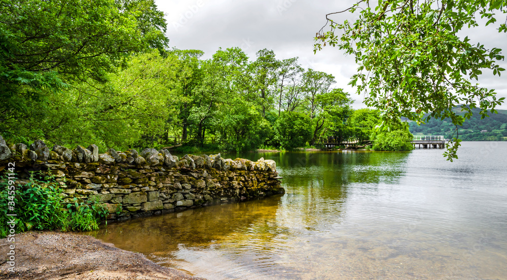 The bank of Ullswater in the Lake District showing the rambling hills and calm water. The bank of Ullswater in the Lake District showing the rambling hills and calm water.