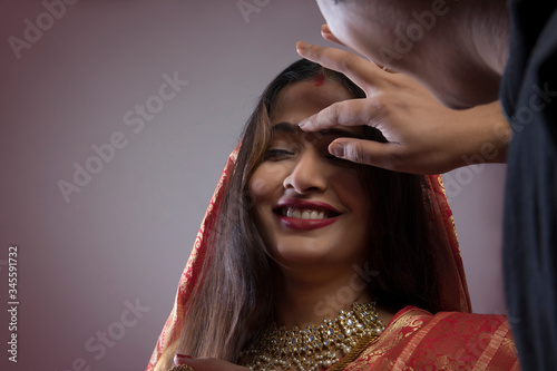 Bengali man putting sindoor on wife's forehead
 photo