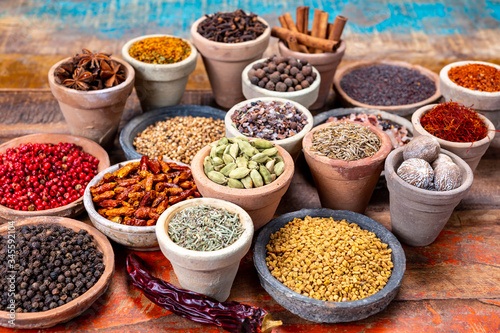 Indian spices collection, dried colorful condiment, nuts, pods and seeds and another spices in clay bowls © barmalini