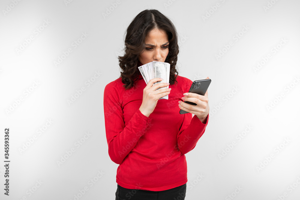 brunette girl holds considers her earned money in her hands on a white background with copy space brunette girl holds considers her earned money in her hands on a white background with copy space