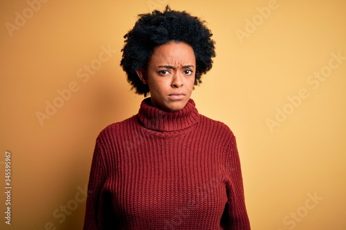Young beautiful African American afro woman with curly hair wearing casual turtleneck sweater skeptic and nervous, frowning upset because of problem. Negative person.