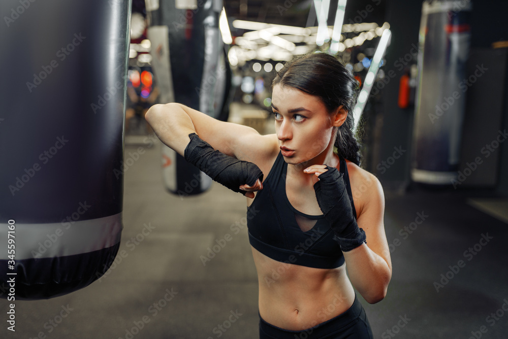 Woman hits a punching bag, thai boxing training