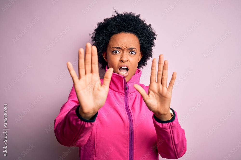 Young African American afro sportswoman with curly hair wearing sportswear doin sport afraid and terrified with fear expression stop gesture with hands, shouting in shock. Panic concept. Young African American afro sportswoman with curly hair wearing sportswear doin sport afraid and terrified with fear expression stop gesture with hands, shouting in shock. Panic concept.