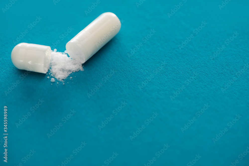 close up view of probiotic capsule with white powder on blue background close up view of probiotic capsule with white powder on blue background