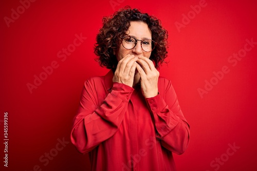 Принти на полотні Middle age beautiful curly hair woman wearing casual shirt and glasses over red